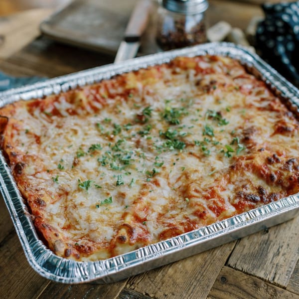 A large pan of Frittella Italian Cafe's baked lasagna with melted cheese and parsley.